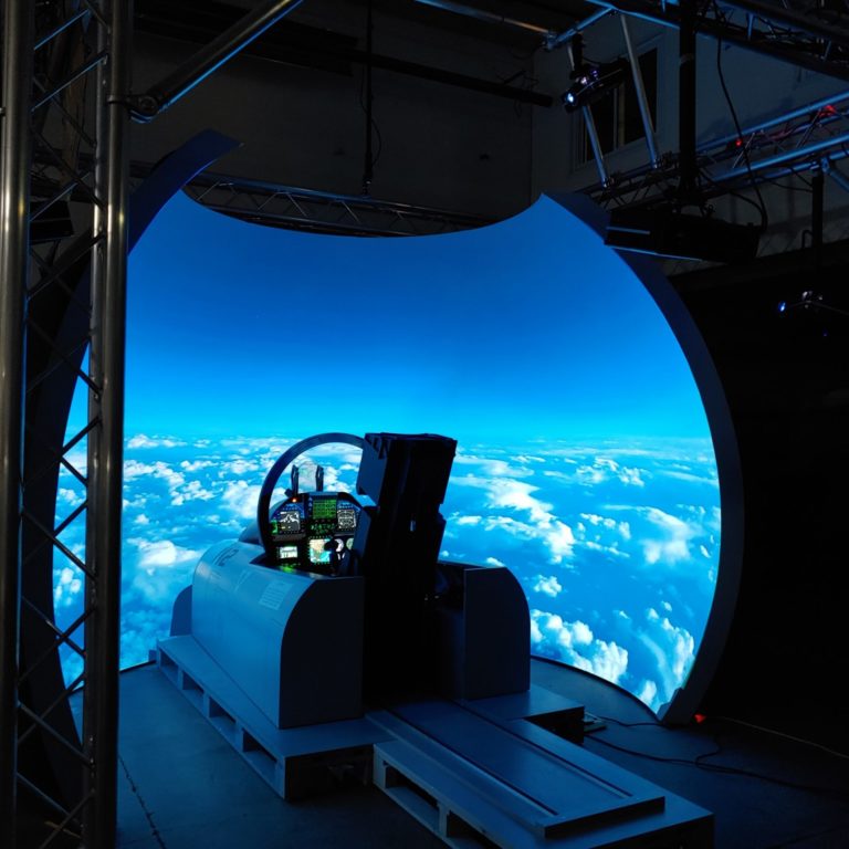 Photo of an illuminated F=18 aircraft simulator dome.