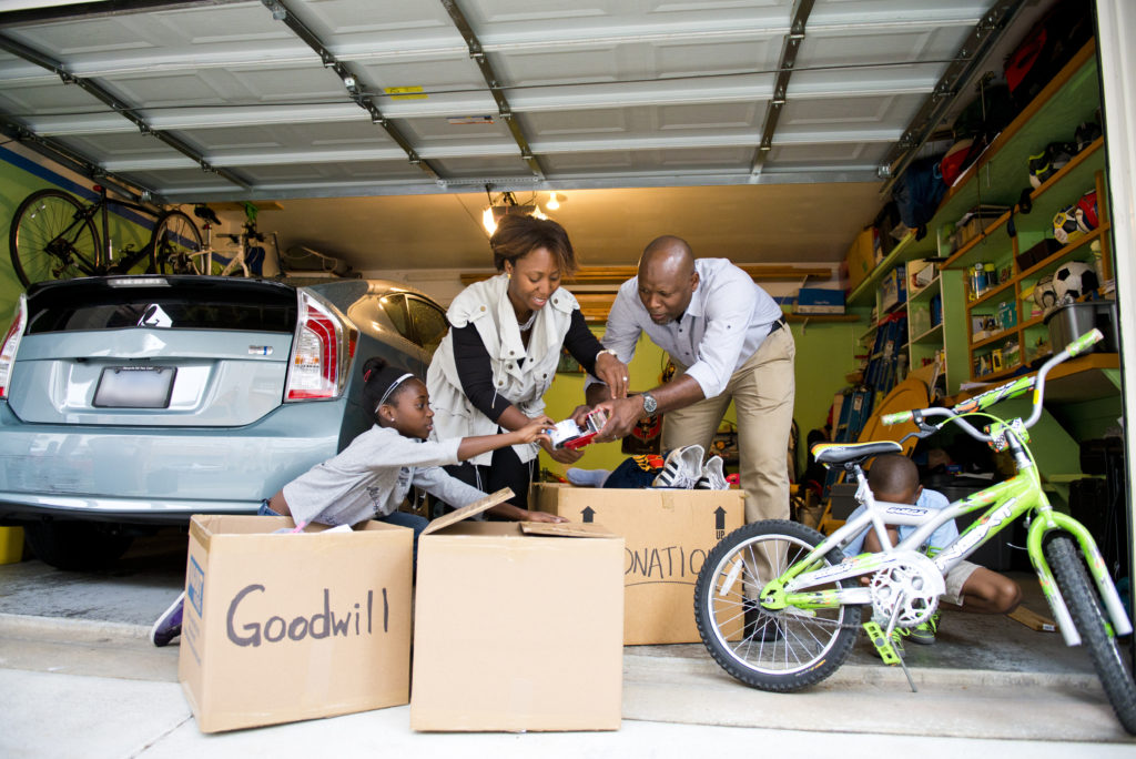 A family inside their garage, preparing boxes of items to bring to the nearest Donation Centre