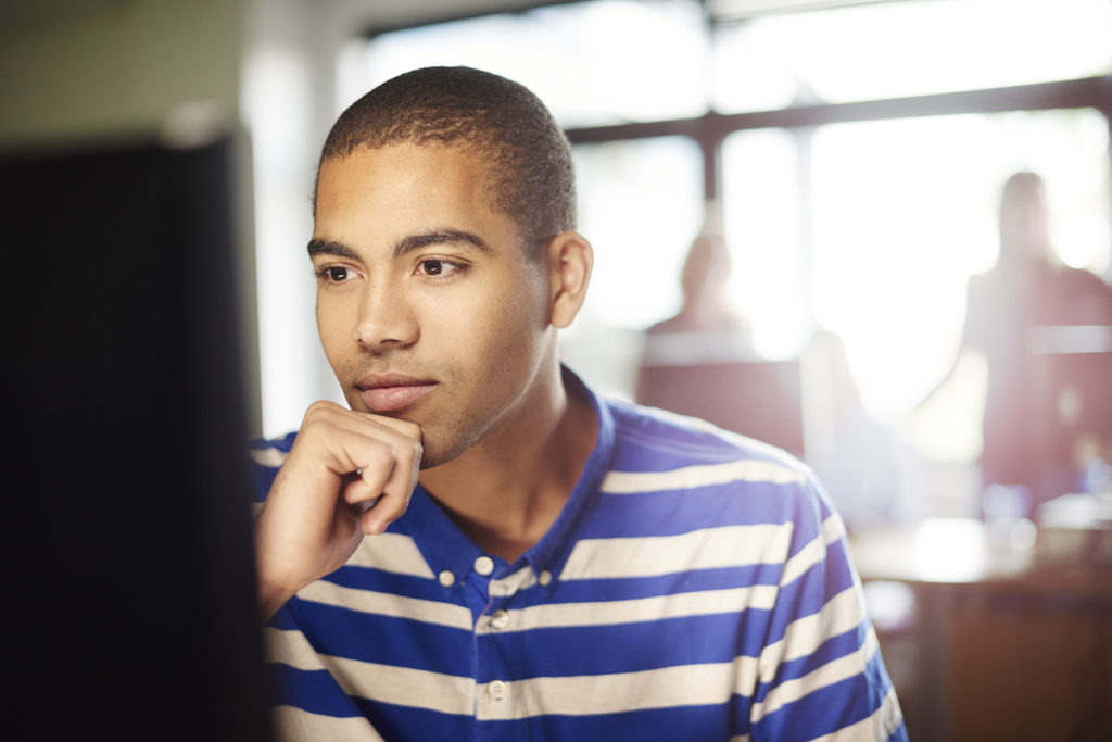 A person in front of the computer with his hand on his chin
