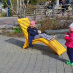 Little girl eating ice cream sitting on yellow chaise lounge