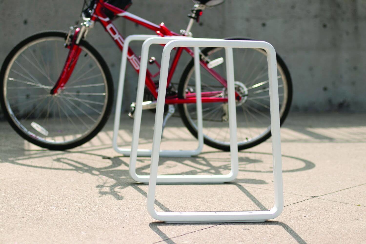 White Iconic bike rack with a red bike behind it