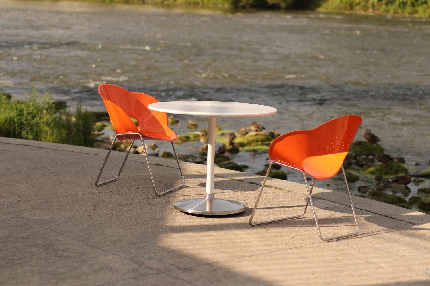Orange chair with a white circular table overlooking a river