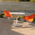 Orange chair with a white circular table overlooking a river