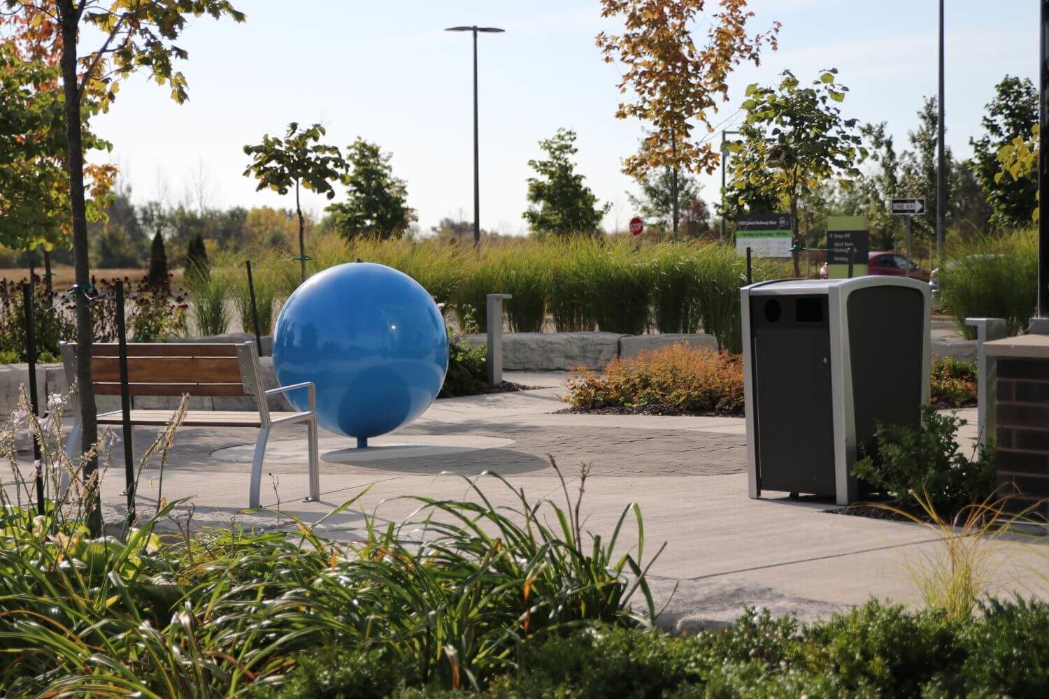 Trash bin near gardens and bench