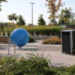 Trash bin near gardens and bench