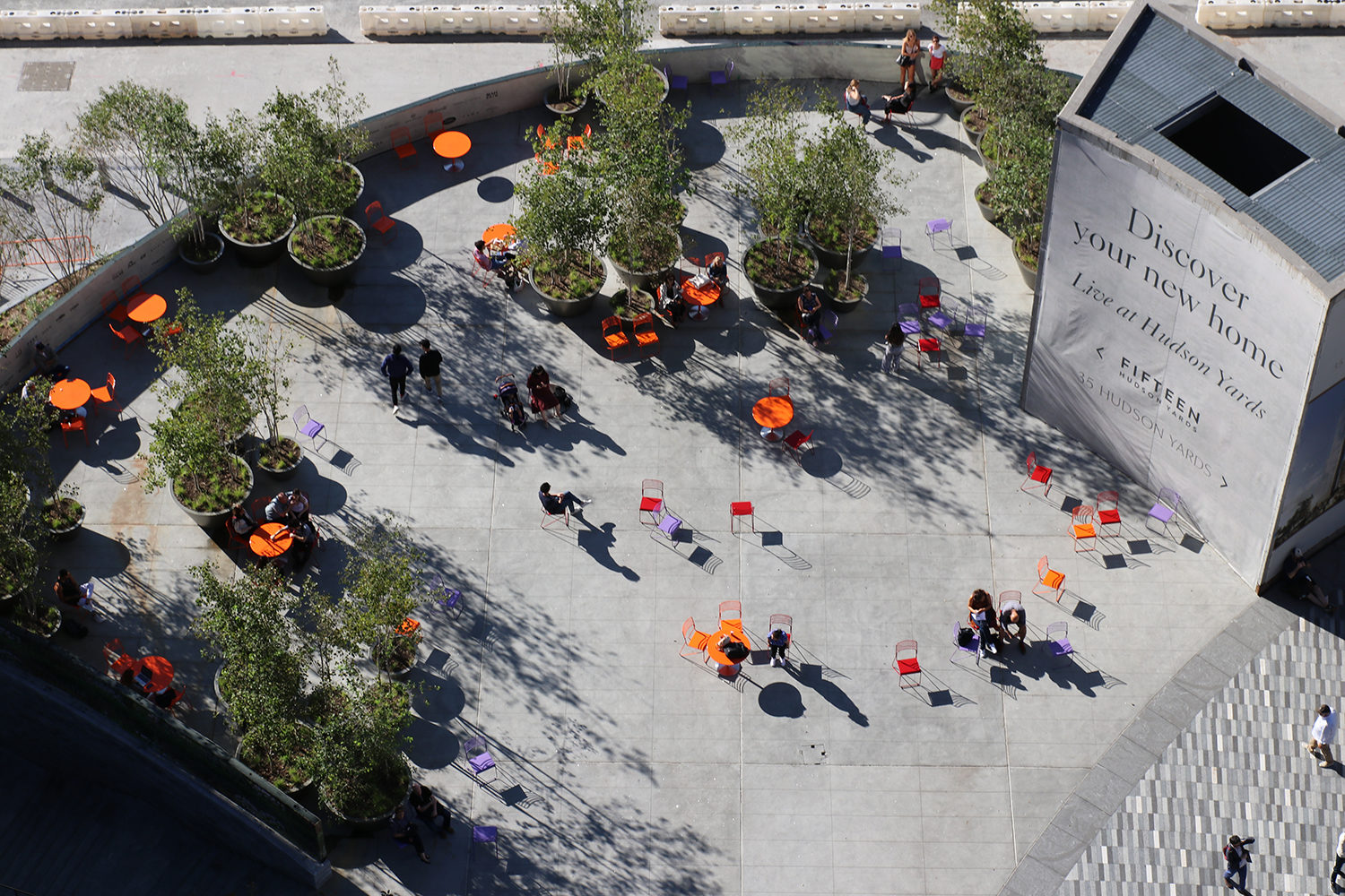Looking down at Hudson Yards from the Vessel at brightly colored tables and chairs