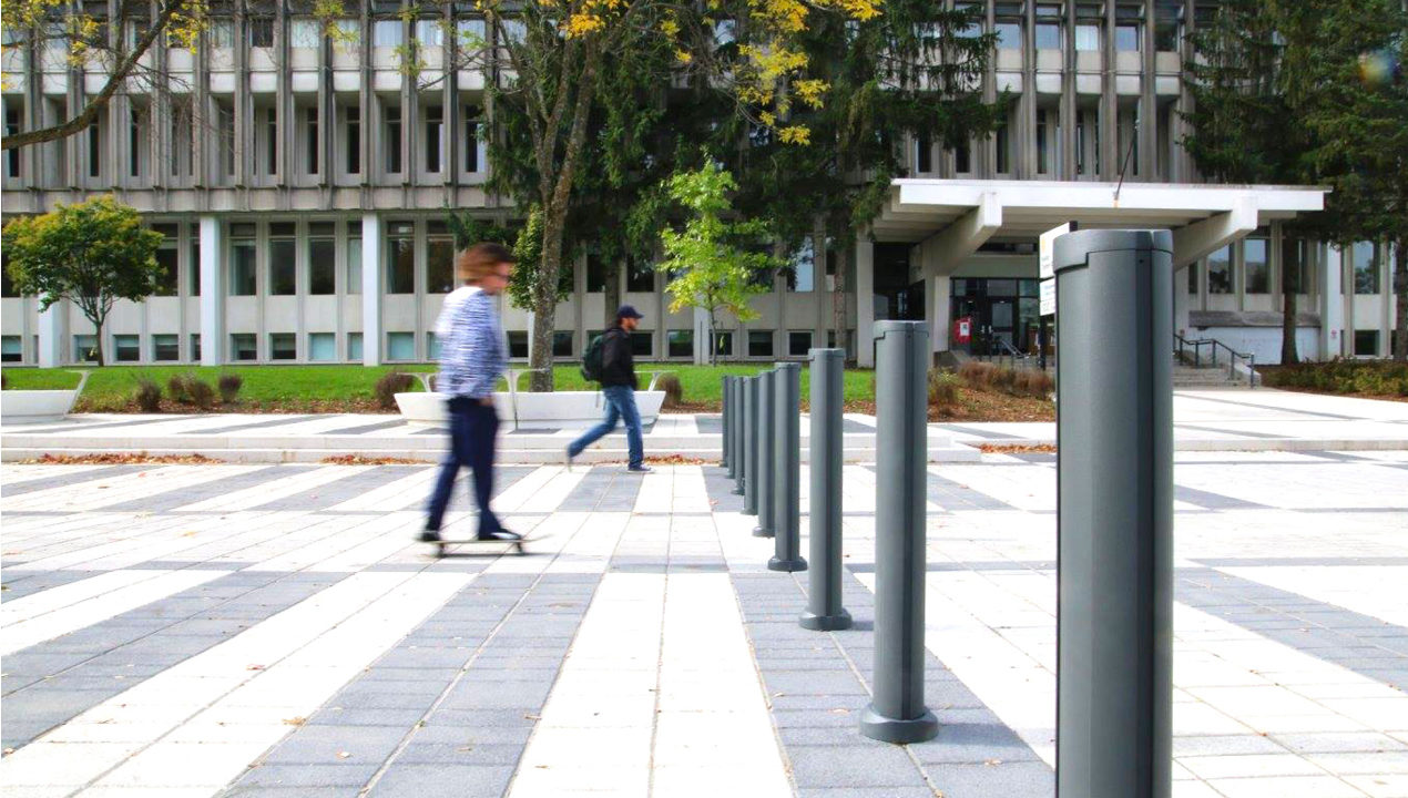 Two Individuals Skating Towards Bollards