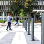 Two Individuals Skating Towards Bollards