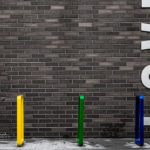 Bright Coloured Bike Racks near brick wall that says 