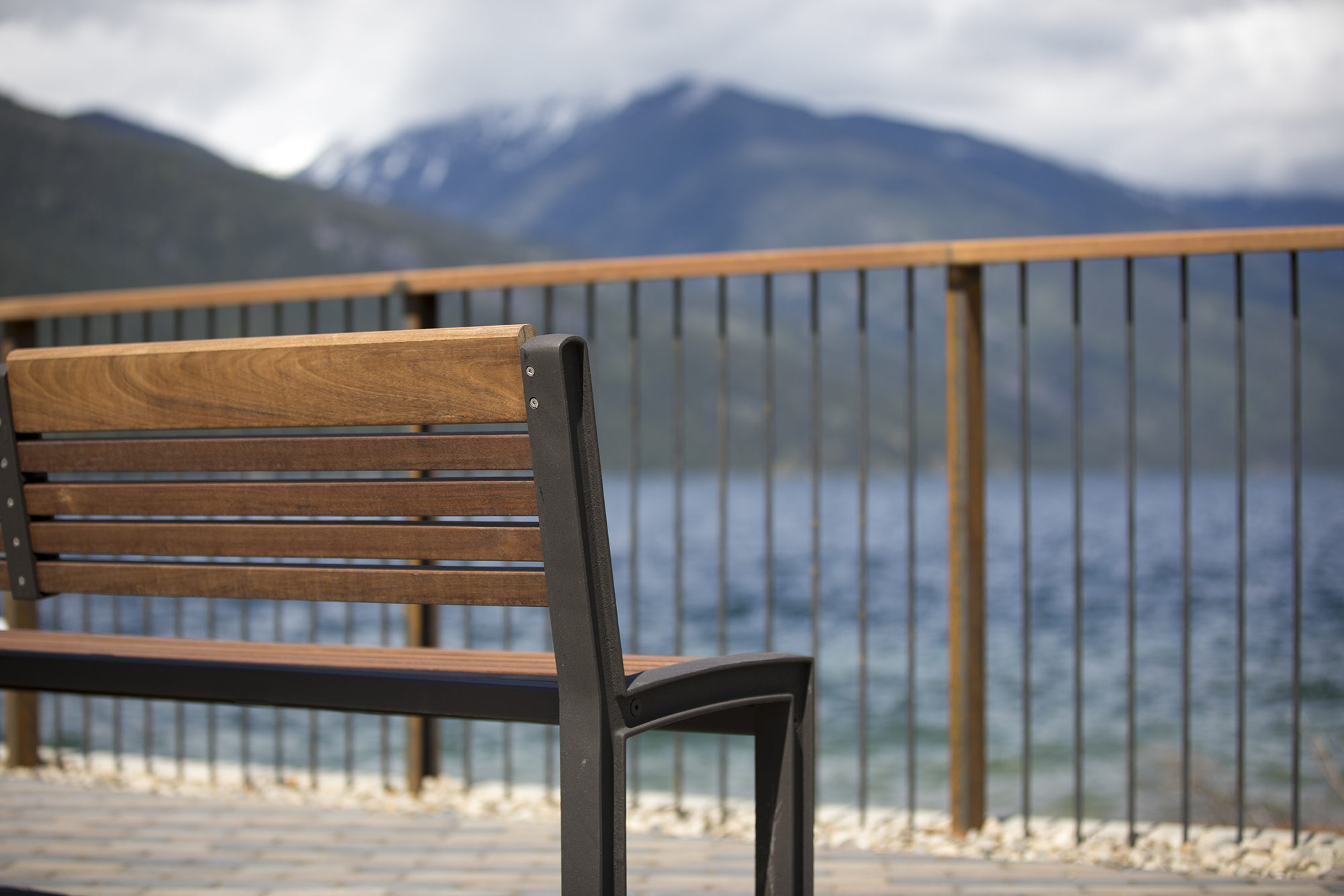 Closeup of the back of a wooden bench in the foreground, blurry mountains beyond