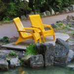 Yellow 720 Chairs surrounded by rocks and a pond