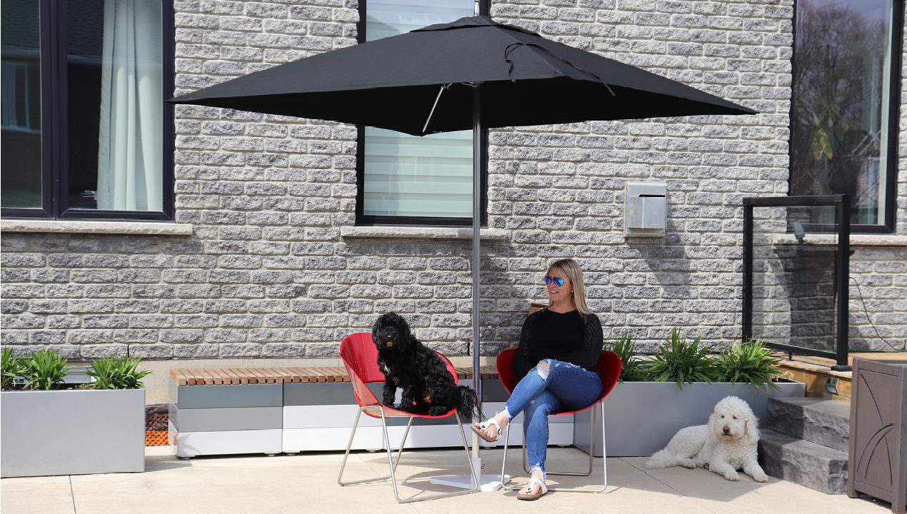 Jill Roberts sitting on battery chairs being shaded by a Tuuci Umbrella
