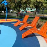 Three Orange 720 Lounge Chairs face a splash pad in a park.