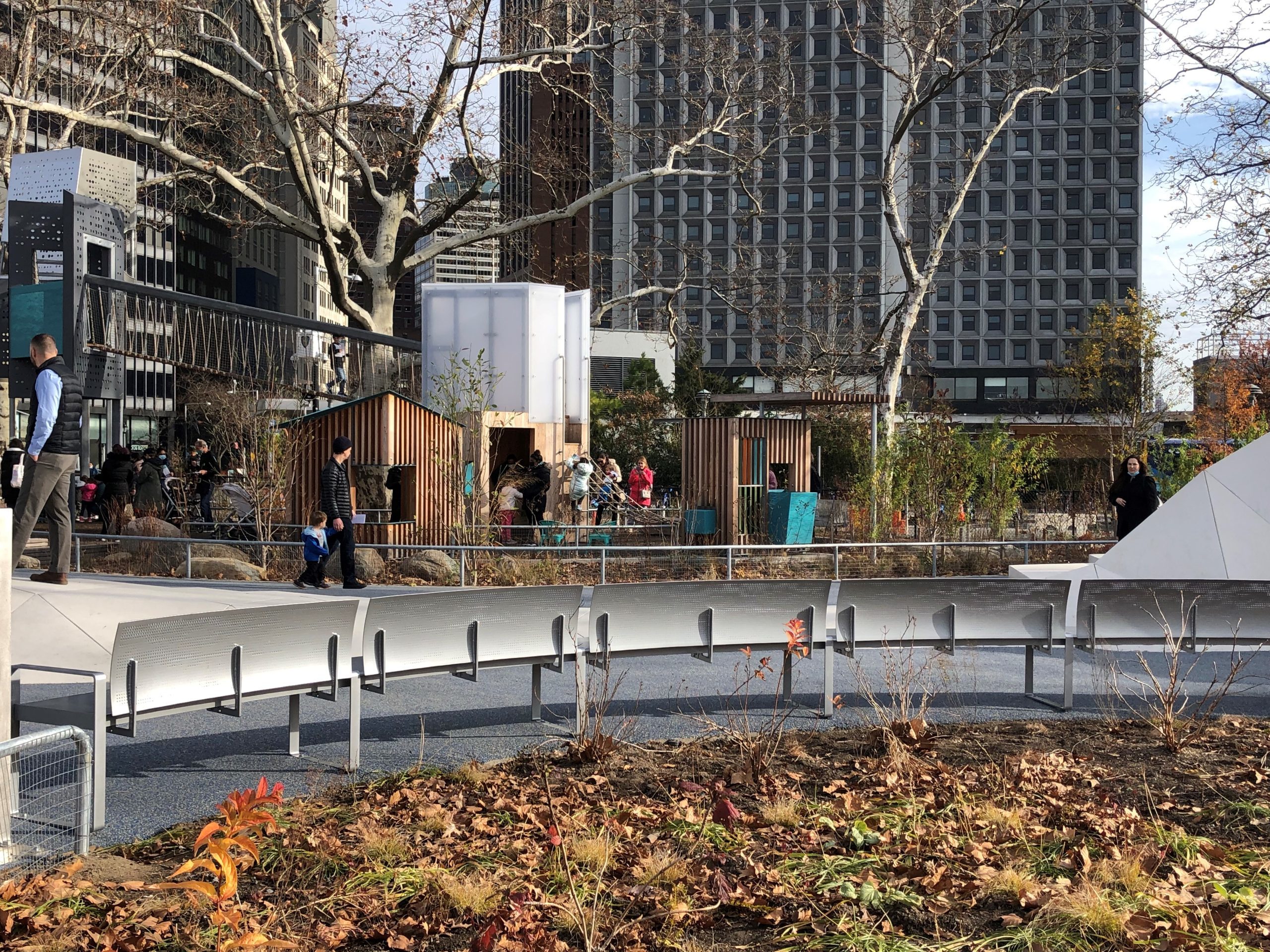Back of custom perforated bench in foreground in front of playground