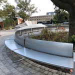 Curved perforated steel bench wraps around a planted area in Battery Park