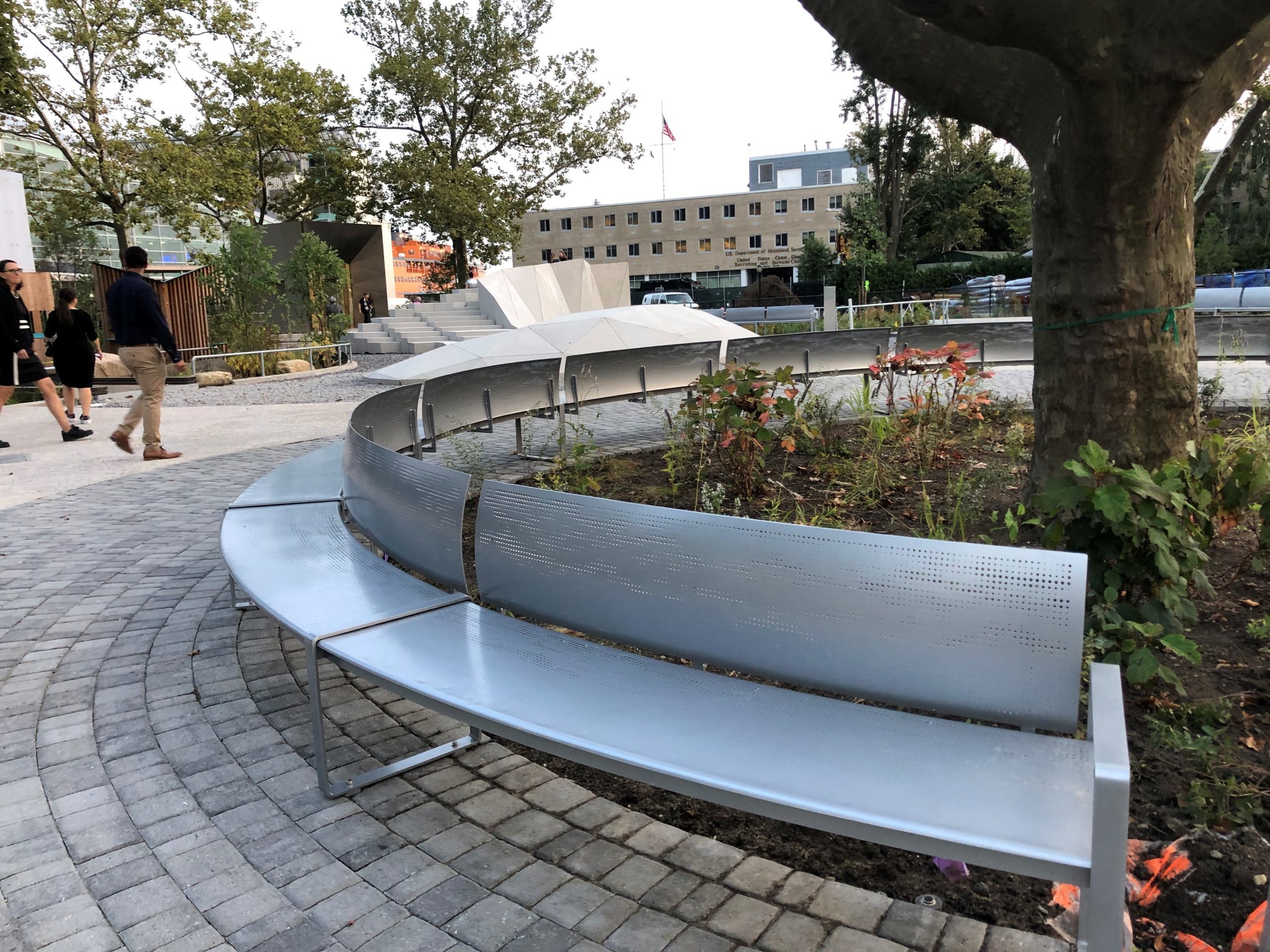 Curved perforated steel bench wraps around a planted area in Battery Park