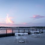 Evening view of white Foro tables and chairs overlooking the ocean from the Stewart McKelvey rooftop terrace