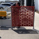 A man attaches a Maglin FLEXX panel to its bracket outside on a concrete surface.