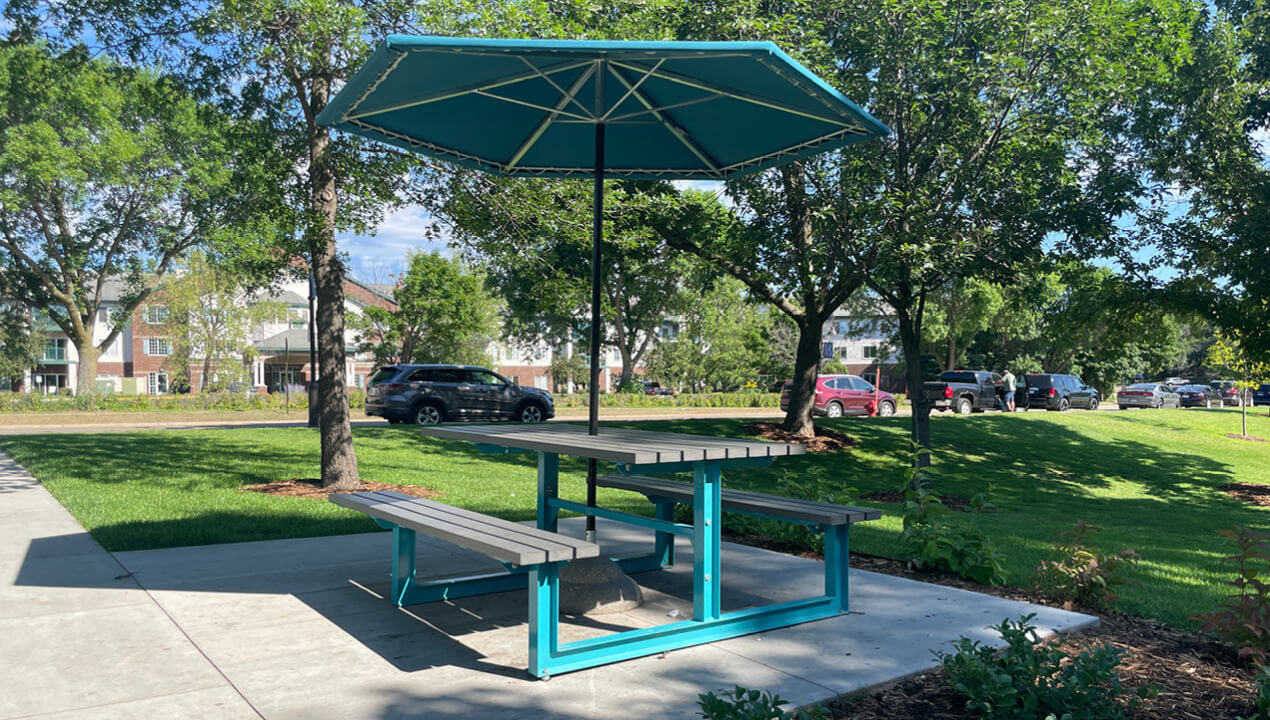 210 Cluster Seating with umbrella at park against green grass and trees