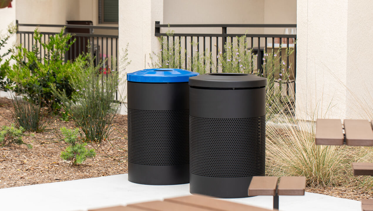600 Waste and Recycle Containers painted black finetex on a patio next to a garden