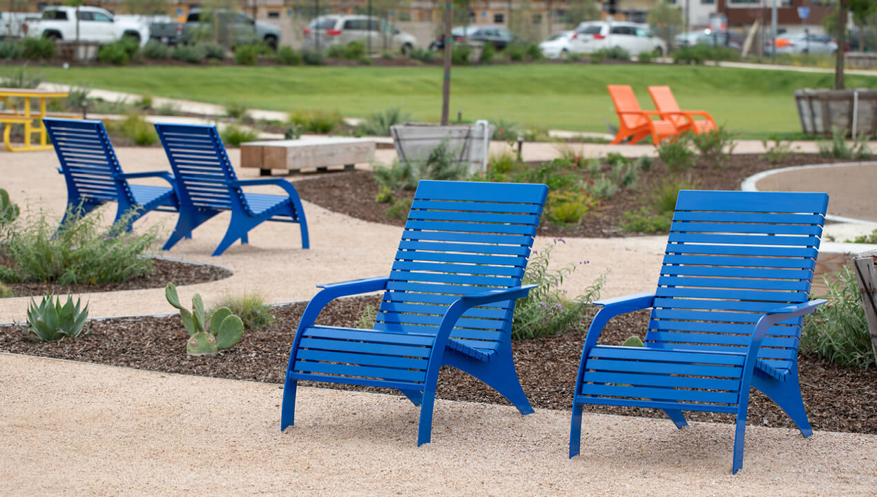 720 Chairs in gloss blue with orange chairs in the background in a park plaza