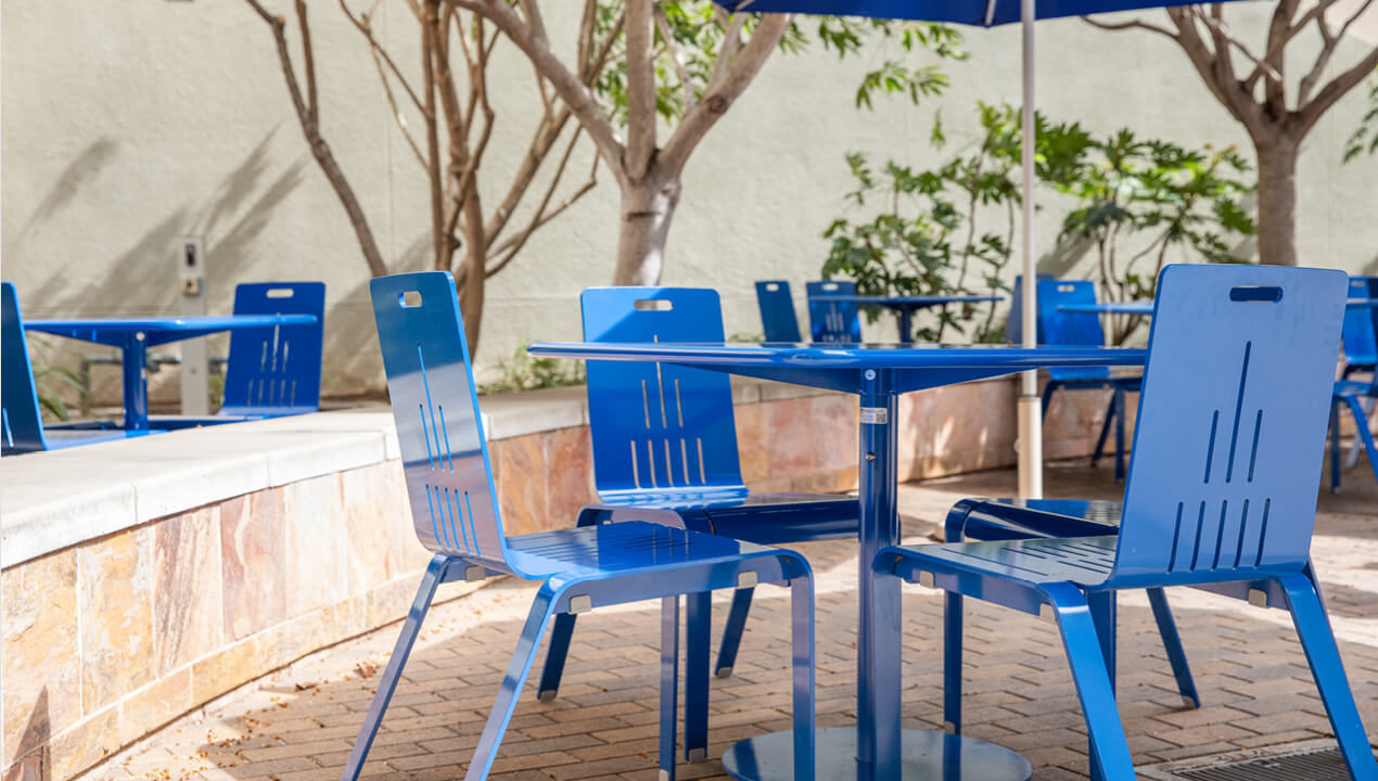 maglin-alum-chairs_blue ALUM Chairs painted bright blue with a Foro table on a patio with trees in the background