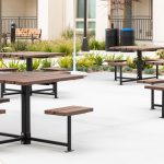 Maglin 400 Series cluster seating units are installed in an amenity courtyard at an apartment complex in Chula Vista, CA. A maglin Iconic Collection bench and waste and recycling containers are in the background as well as a bed of green plants.