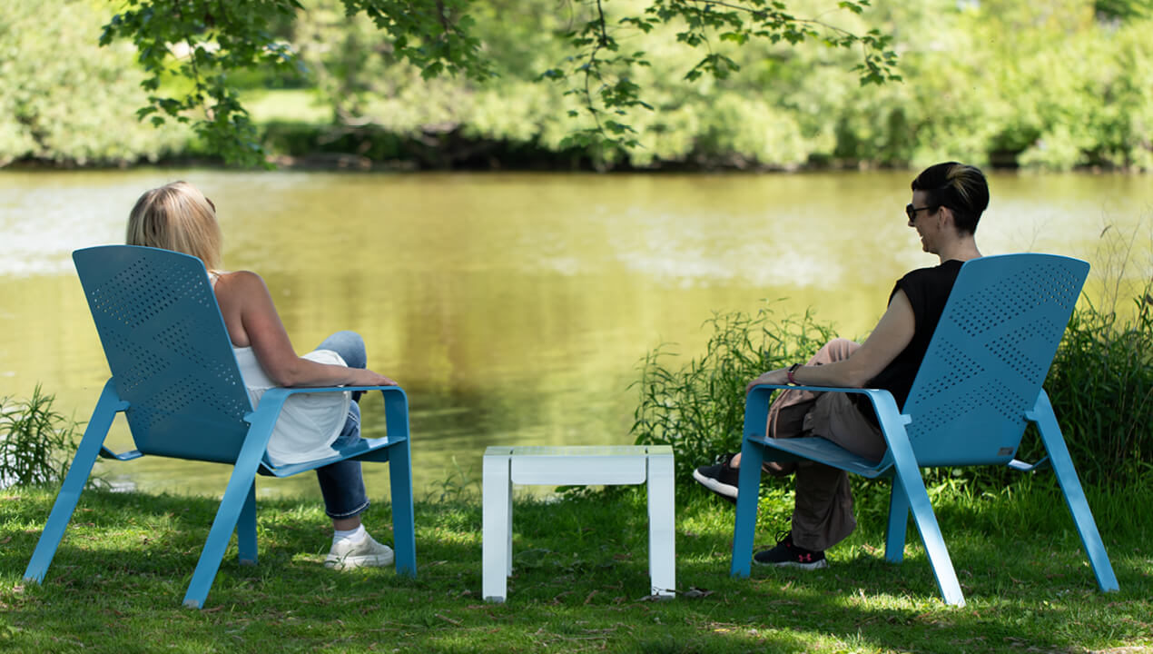 maglin-alum-lounge-chairs-water ALUM Collection lounge chairs with lounge table powdercoat pastel blue and white with women laughing and enjoying the scenic landscape