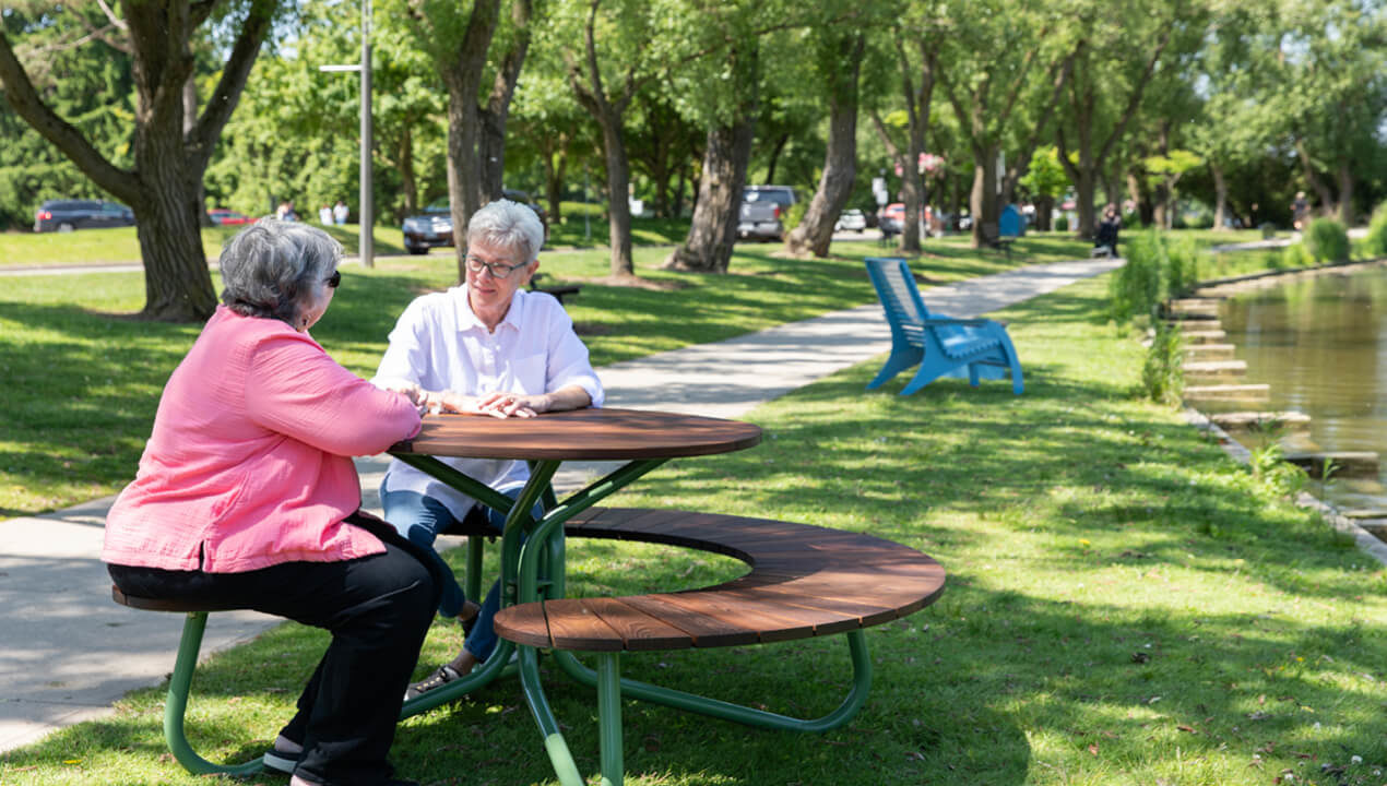FAVA Cluster Seating with wood, quad and single seat along trail with two ladies enjoying a break
