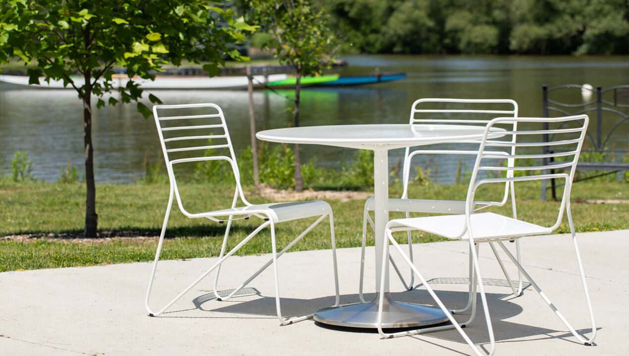 Powdercoated white Kontur Chairs with Battery Table on concrete pad next to lake