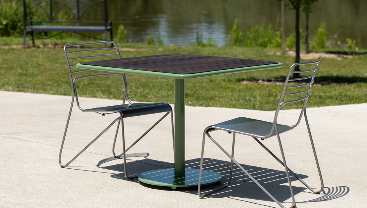 Foro table with thermally modified ash wood top and kontur chairs next to greenery and lake