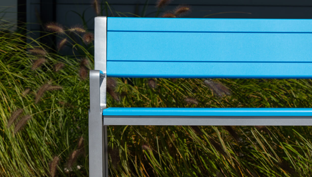 Backed 970 Bench with High Density Polyethylene seat and back in blue, with grasses in background