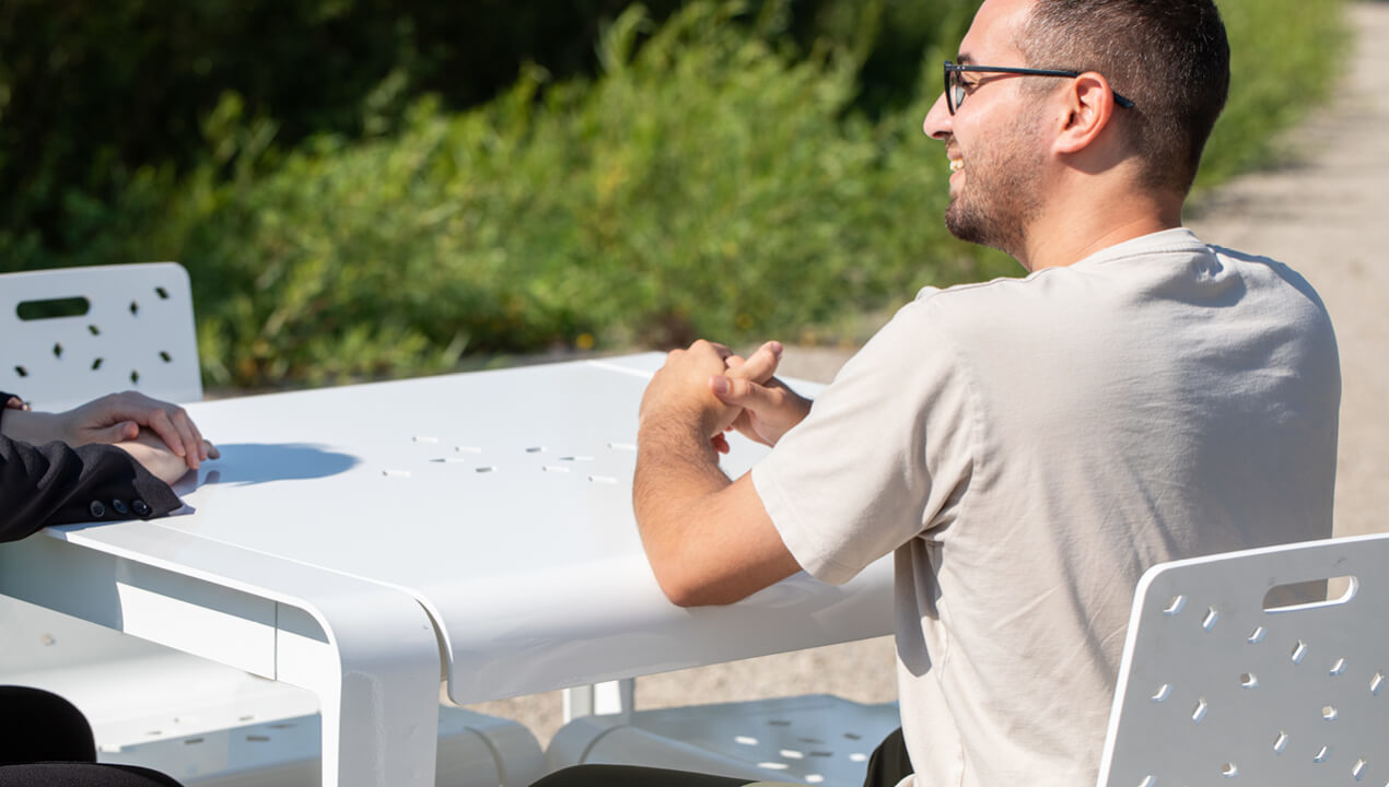 Close-up of ALUM table in white powdercoat with man smiling while seated