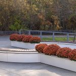 CANOE modular planters with orange mums and bench seating on a fall day