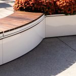 White powdercoated CANOE modular planters with Ogden bench seating and orange mums