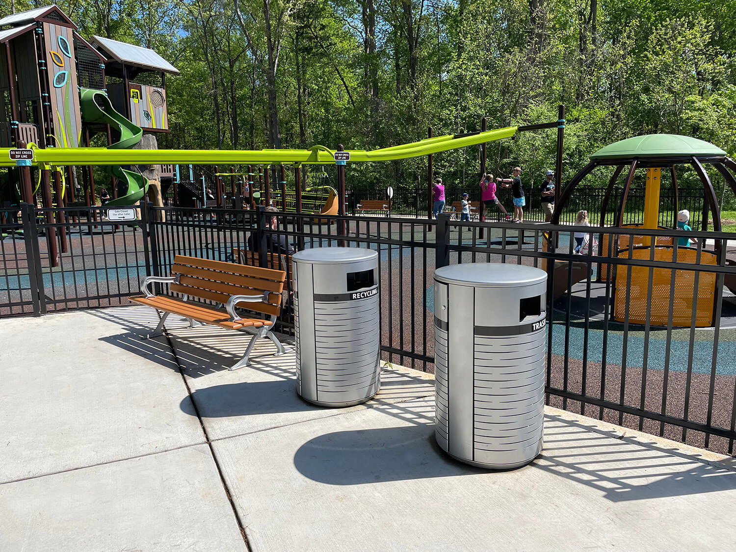 A backed Maglin bench sits with some waste and recycle containers in front of Rosedale Nature Park