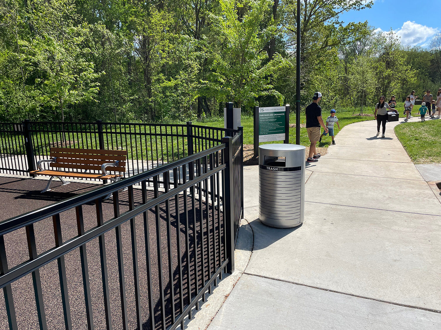 Rosedale Nature Park surrounding by lush trees and a pathway leading to the park with Maglin's benches and trash containers