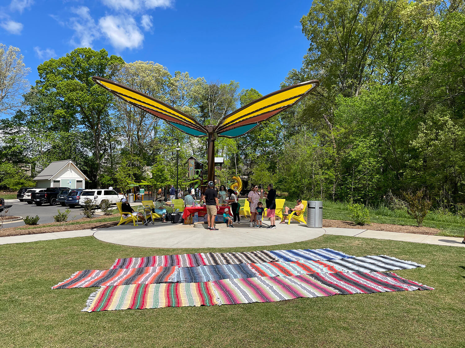 Butterfly shade structure providing shade for a family celebrating an event, whilst sitting on yellow 720 Maglin chairs