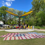 Butterfly shade structure providing shade for a family celebrating an event, whilst sitting on yellow 720 Maglin chairs