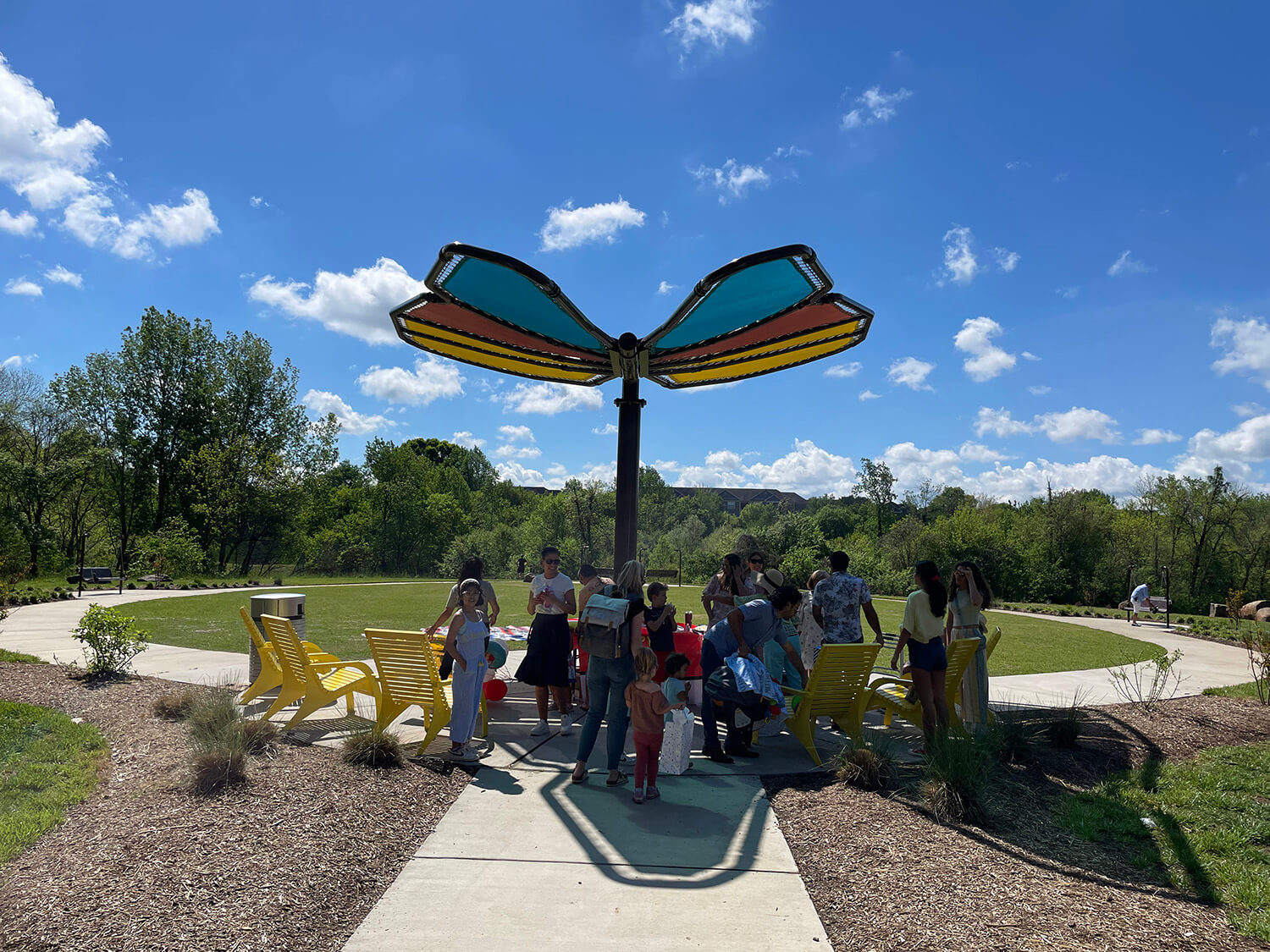 Butterfly shaped shade structure provides shade for family members enjoying the outdoors on Maglin's yellow 720 Chairs