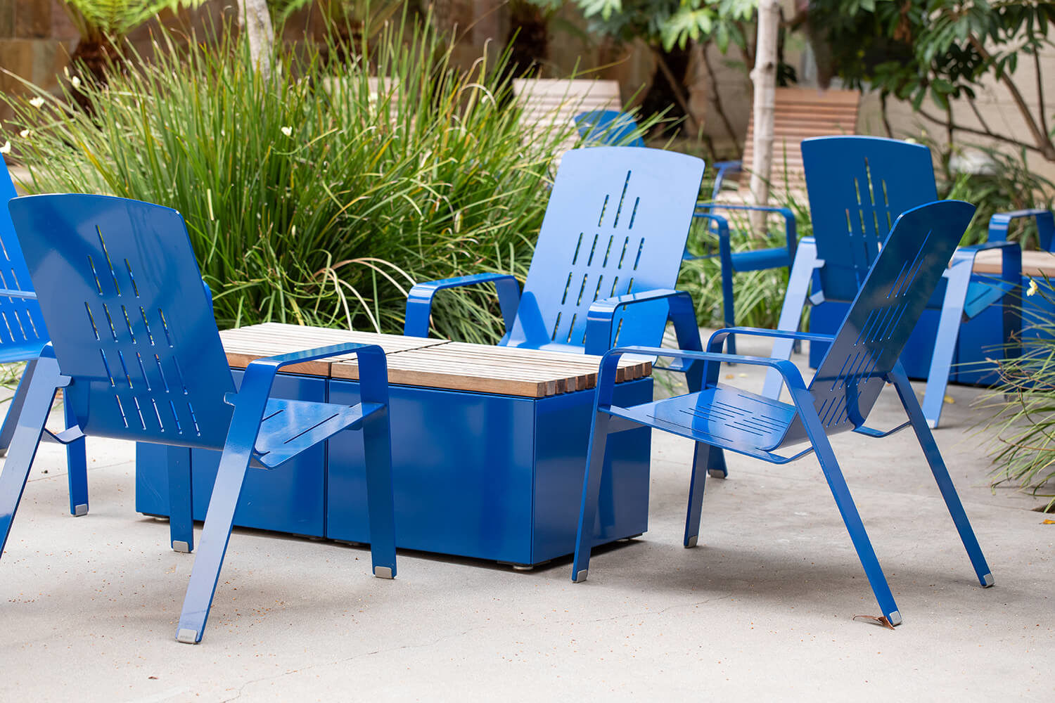 Maglin ALUM Lounge Chairs sit with Pixel coffee tables amongst greenery at CSUSM