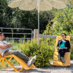 Maglin employees enjoying the fresh air while relaxing on ALUM chaise lounge's under ROMA umbrella shade