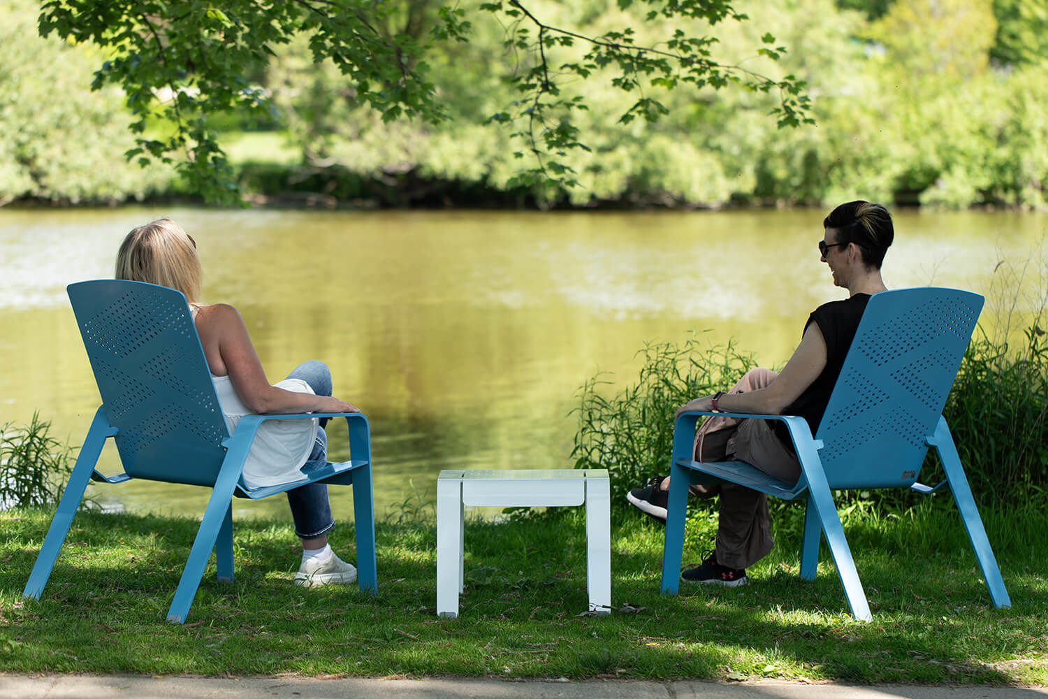 Maglin employees relaxing by the water while sitting in ALUM lounge chairs