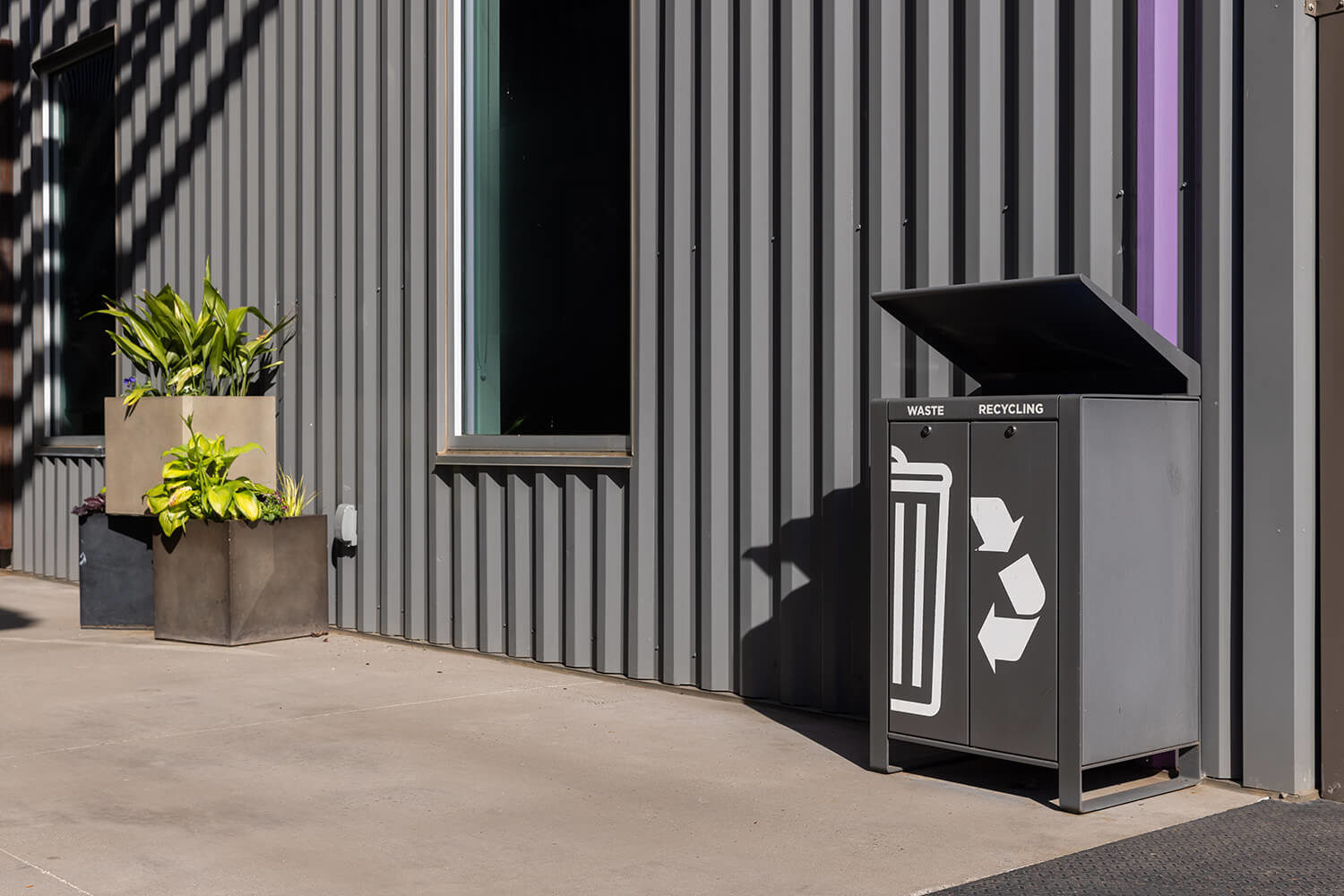 Lexicon waste and recycling station with rain shield at Camp North End sits next to stacked planters