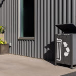 Lexicon waste and recycling station with rain shield at Camp North End sits next to stacked planters