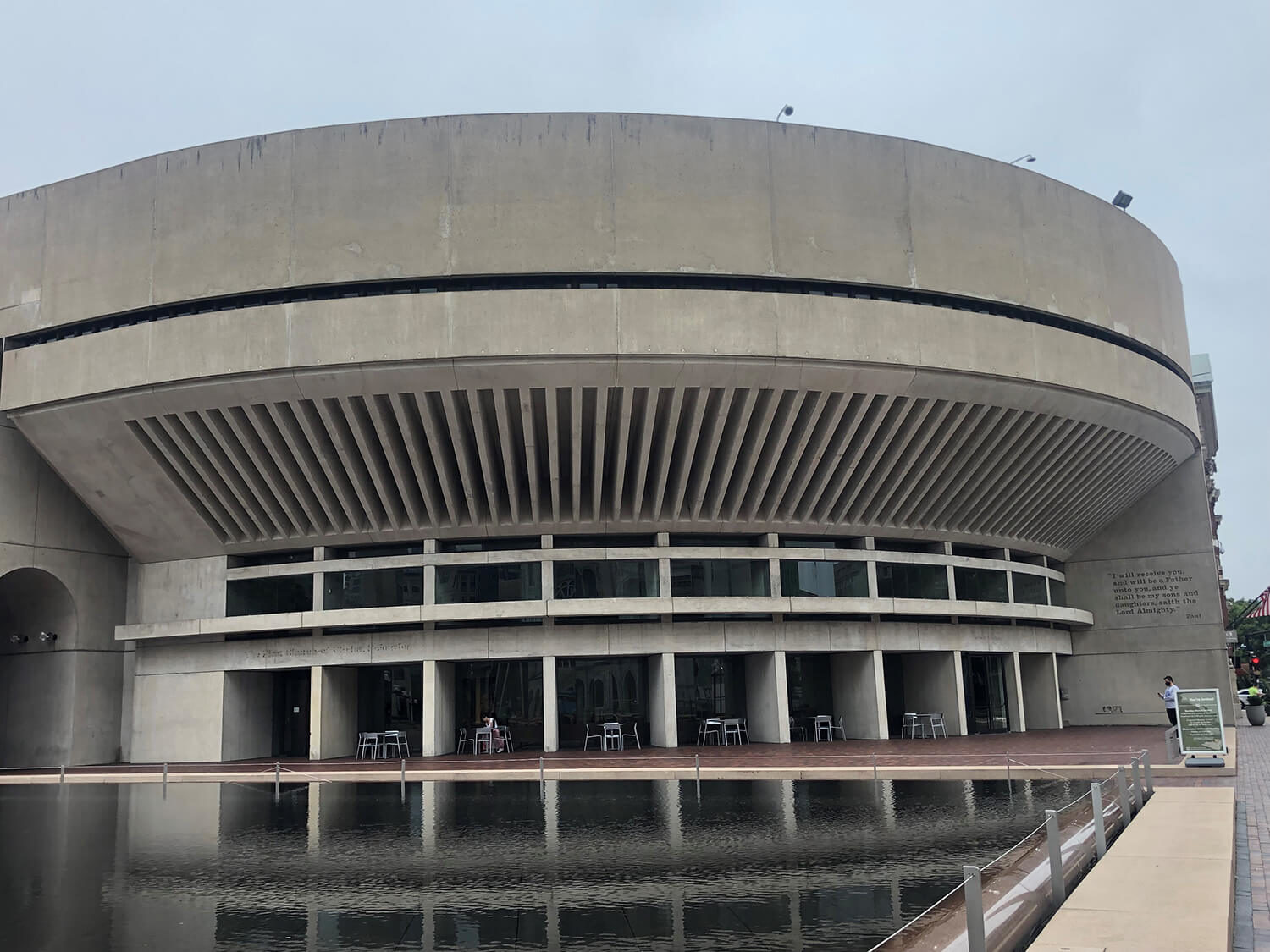 Concrete building with tables and seating next to waterway