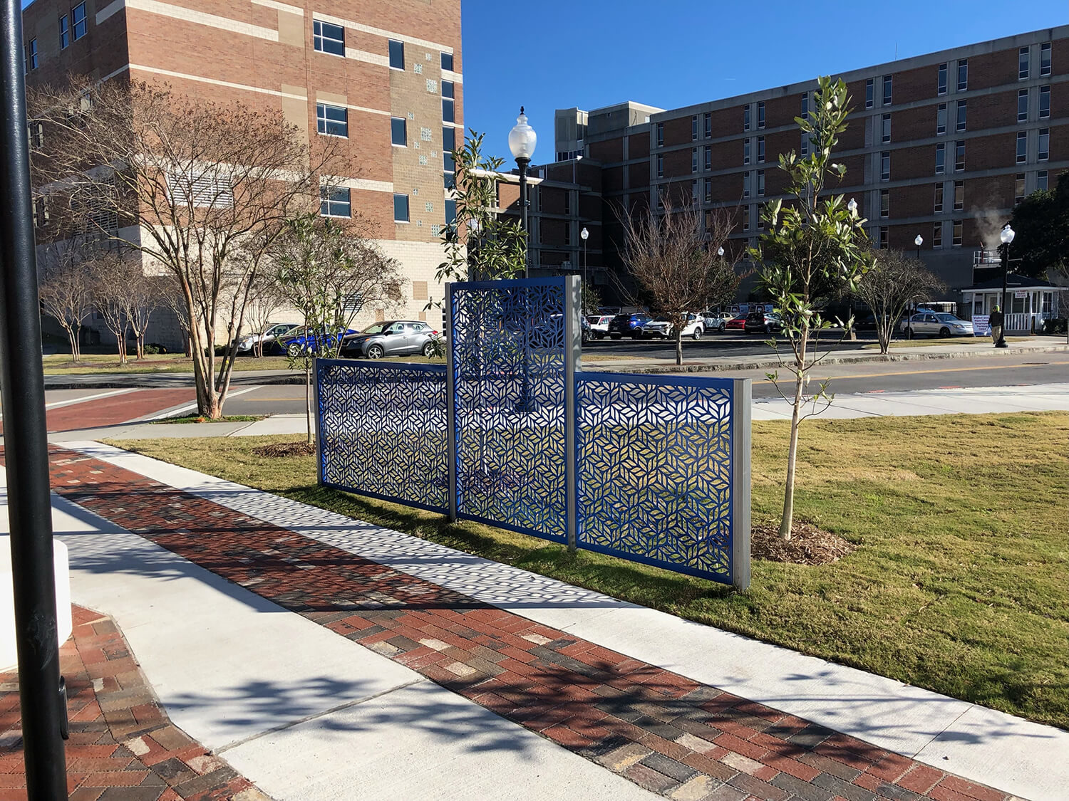 Blue and silver FLEXX panels line a walkway creating privacy from the road