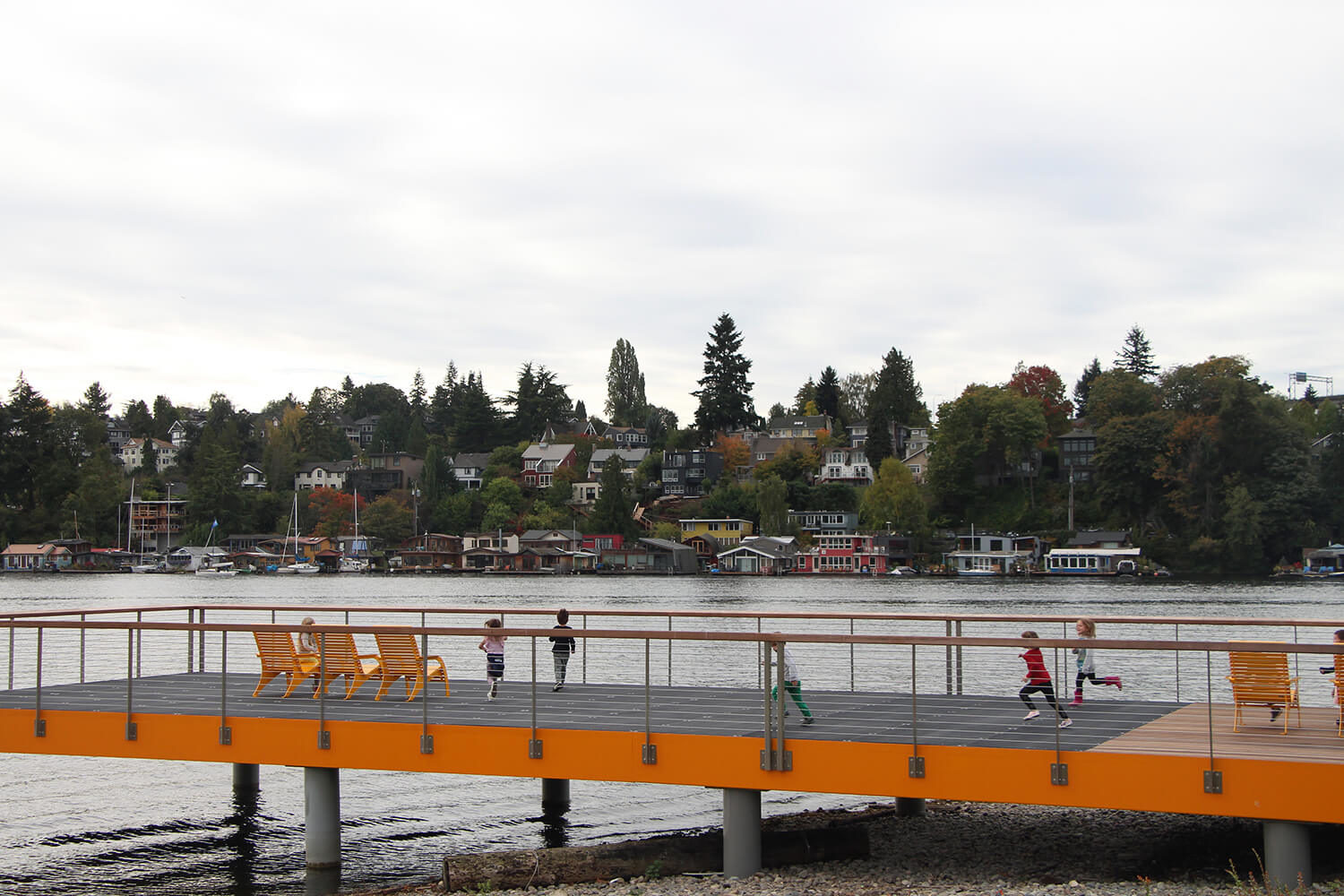 Children running on dock with yellow Maglin 720 chairs overlooking water and houses