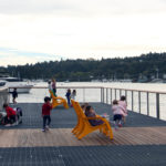 Children playing on dock with bright yellow Maglin 720 chairs overlooking water