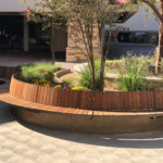 Curved Ogden bench follows the concrete wall on outdoor patio